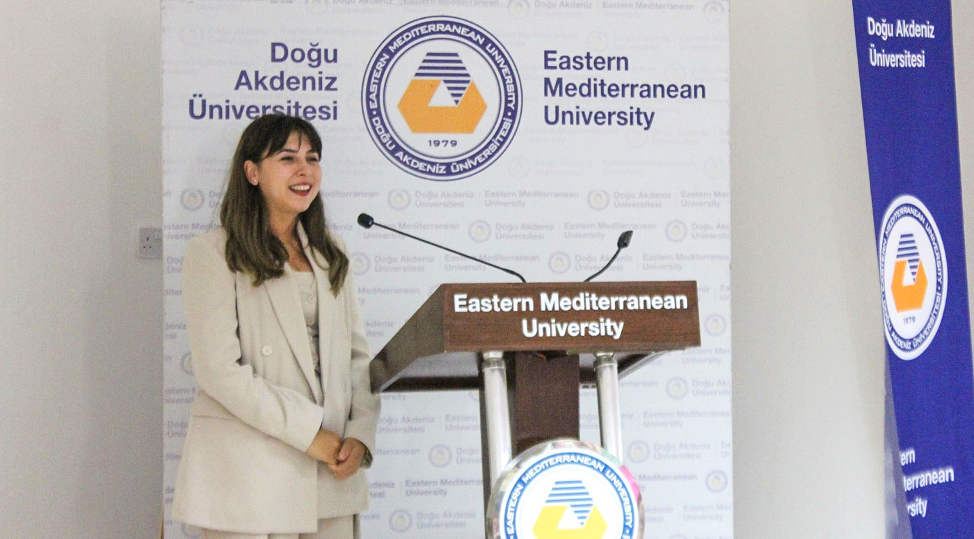 Speaker at the podium in front of the EMU backdrop during the first lecture