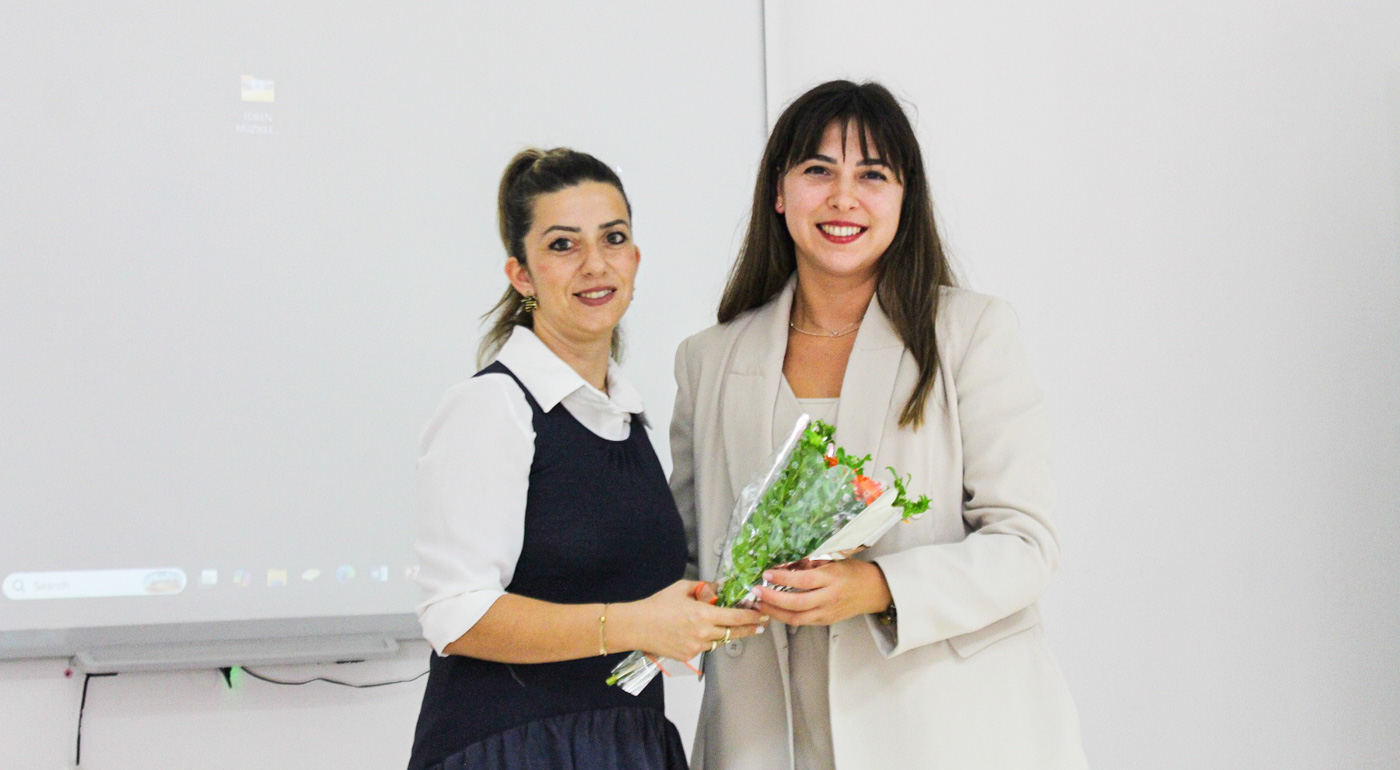 Two women presenting a bouquet of flowers on stage
